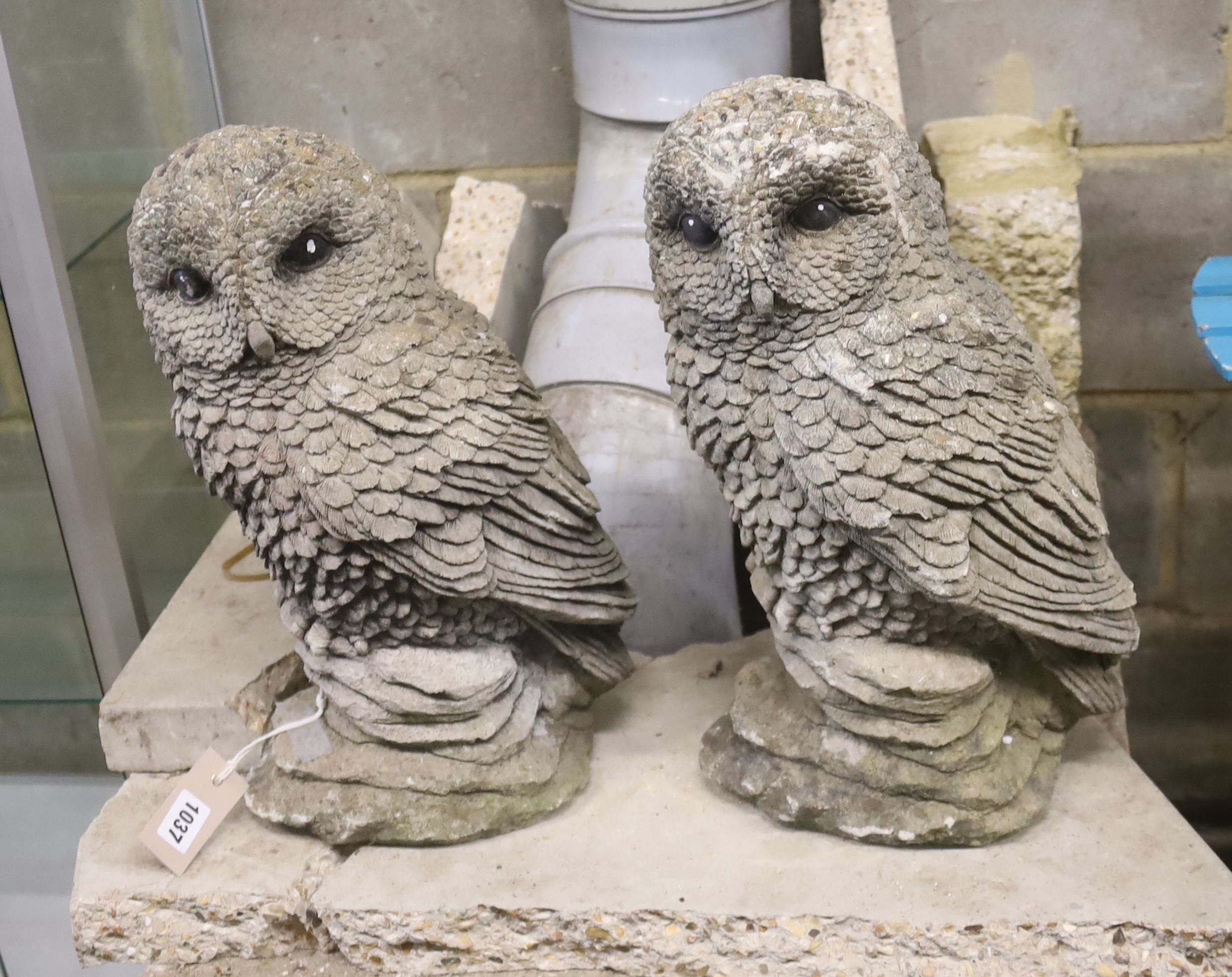 A pair of reconstituted stone garden ornaments modelled as owls, height 41cm